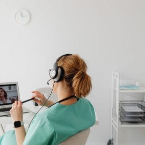 Medical professional conducting an online consultation via video call in a modern office environment.